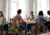 People conversing at small tables in a bright café
