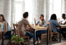 People conversing at small tables in a bright café