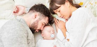 Parents sleeping beside newborn baby