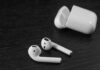 Wireless earbuds with open charging case on dark wood