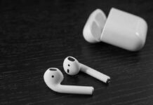 Wireless earbuds with open charging case on dark wood