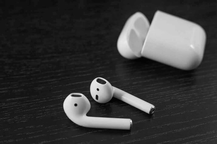 Wireless earbuds with open charging case on dark wood