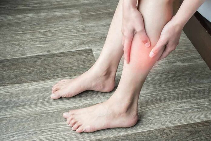 shutterstock_1421196494 person holding calf with red area indicating leg pain