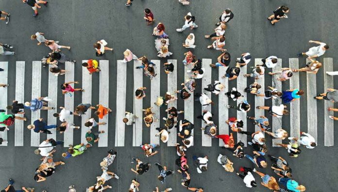 Crowd of pedestrians crossing a zebra crosswalk from above