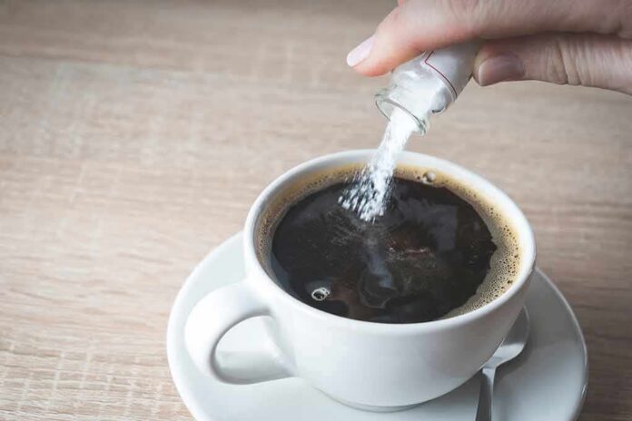 shutterstock_1648504252 hand pouring sugar into a cup of black coffee