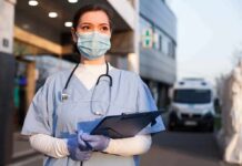CDC Bombshell: Half Your Health Isn’t Medical Healthcare worker in scrubs wearing mask and gloves holding a clipboard