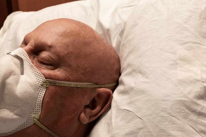 Elderly man wearing a face mask resting on a pillow