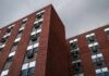 Brick apartment buildings with window air conditioners under cloudy sky