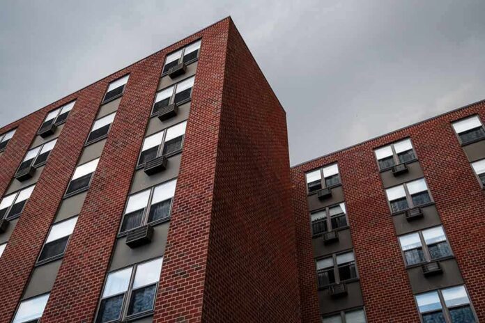 Brick apartment buildings with window air conditioners under cloudy sky