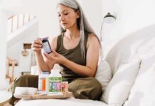 Woman reading supplement bottle label on a sofa