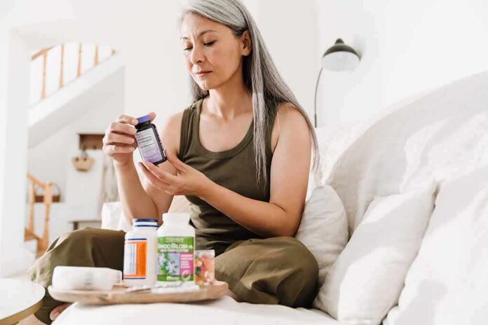 Woman reading supplement bottle label on a sofa