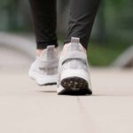 Close-up of person walking in gray sneakers