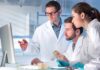 Scientists in lab coats reviewing data on a computer