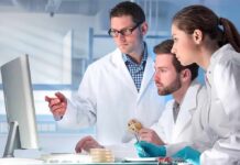 Scientists in lab coats reviewing data on a computer