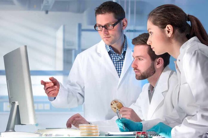 Scientists in lab coats reviewing data on a computer