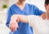 Physical therapist guiding a patient's arm during shoulder exercise