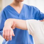 Physical therapist guiding a patient's arm during shoulder exercise
