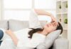 Hangover Hacks Doctors Swear By Woman lying on sofa with hand on forehead
