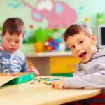 Two young boys playing with colorful shapes at a classroom table