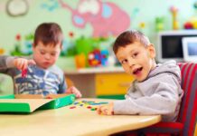 Two young boys playing with colorful shapes at a classroom table