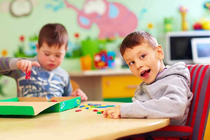 shutterstock_610735670 Two young boys playing with colorful shapes at a classroom table